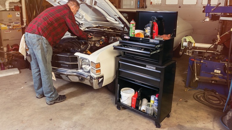 Craftsman 5-Drawer Tool Center in garage next to man repairing car