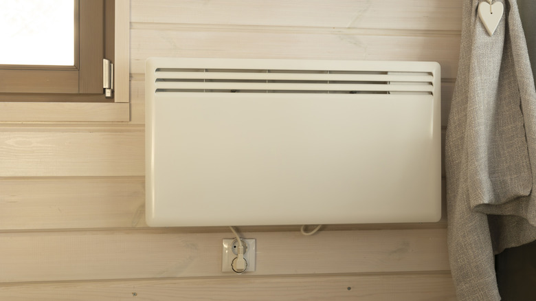 An electric heater on a wall next to a window