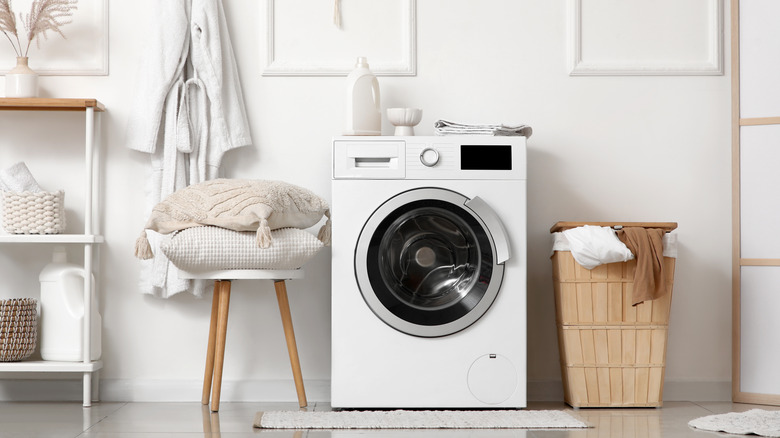 The interior of an all-white and neutral-hued laundry room