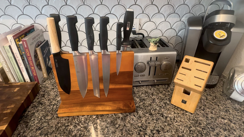 A carpenter shows off a magnetic wooden counter stand with knives stuck to it.