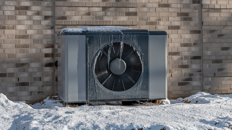 A heat pump covered in icicles and surrounded by snow
