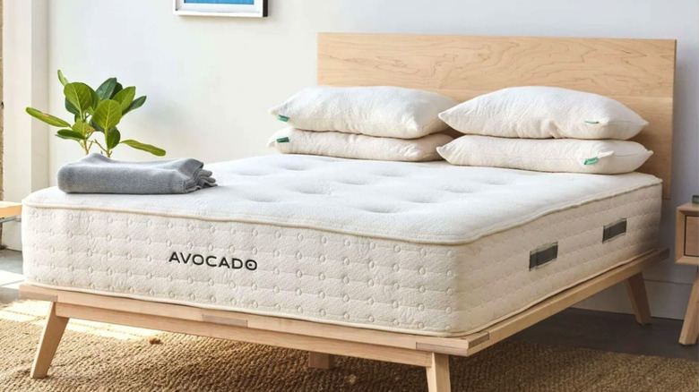 Avocado 11" matress with four pillows on a wood frame in a bedroom
