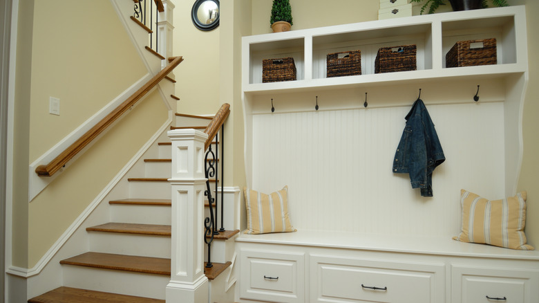Hall tree with hooks, cubbyholes, drawers, and a bench next to a staircase.