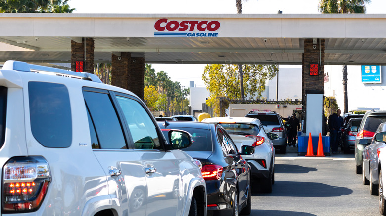 A series of cars in front of a Costco gas station, with all spots full