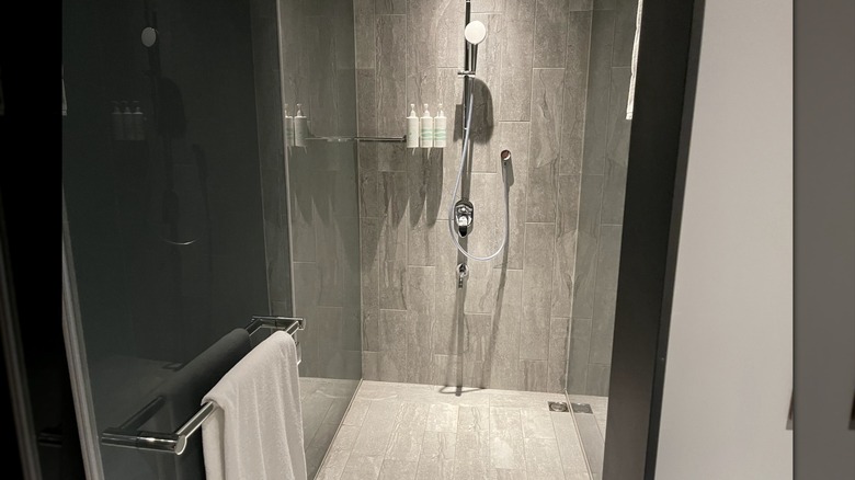 A shower with stone tiles and a towel hanging on the door