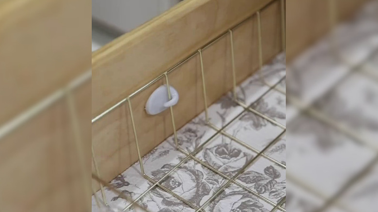 A wire tray divider affixed on a small self-adhesive hook