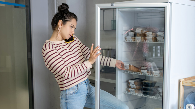 Woman opening a glass door fridge