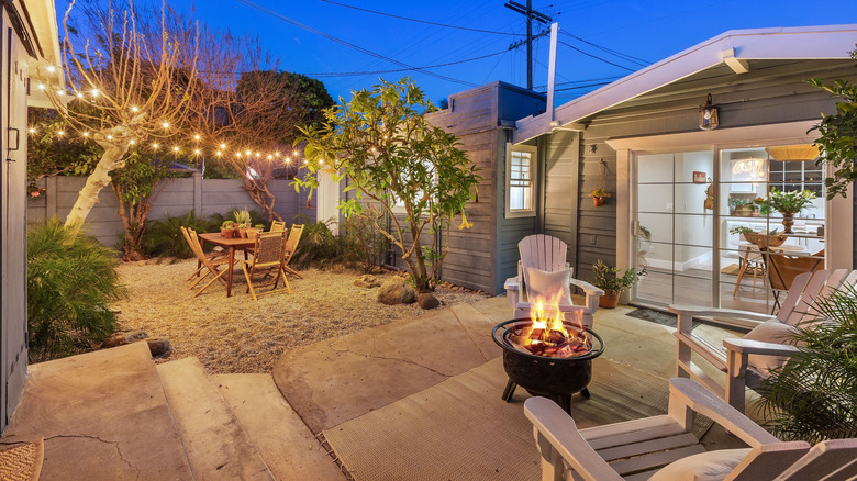 Cozy outdoor patio with string lights over a dining area and a fire pit around a sitting area