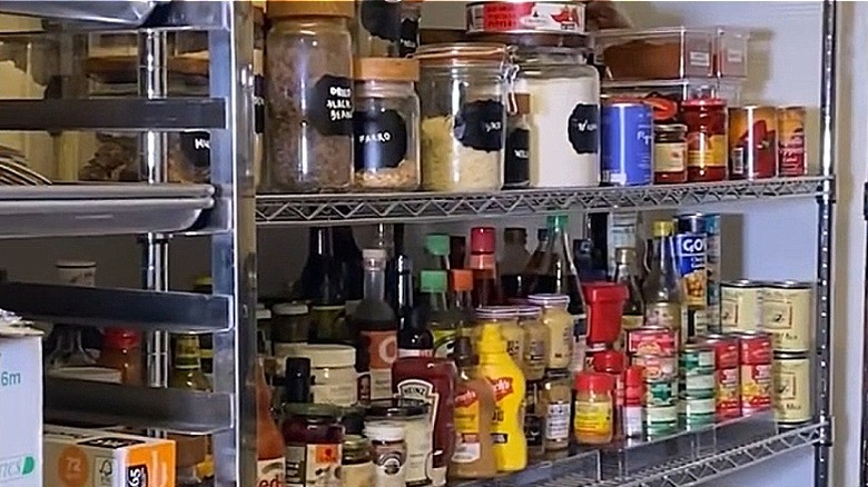 Shelves in Bobby Flay's pantry with various storage containers on metal shelves