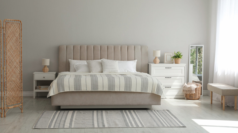 Striped bedding and rug in a neutral room brings out the vertical texture in a headboard