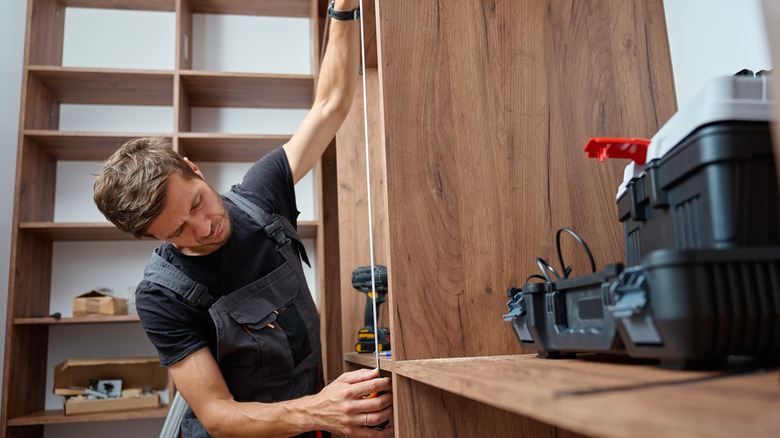 man building built-in bookcase