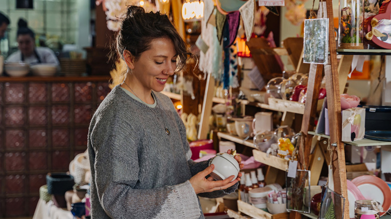 Woman in a shop holding a pottery piece among many other miscellaneous items