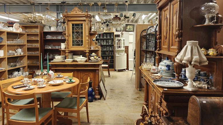 Thrift store area with kitchen and dining room items, wooden cases, a dining table set, and glassware