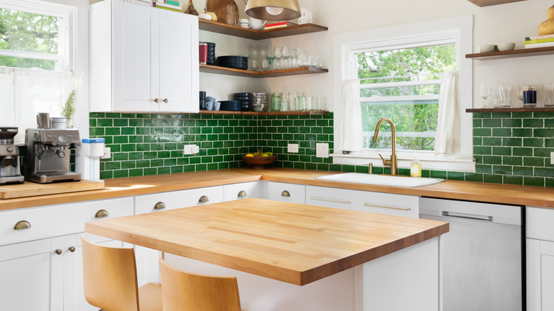 Modern kitchen with white tiles, wood counter tops, and green subway backsplash tiles