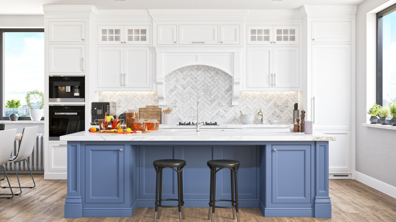Modern kitchen with white cabinets running all the way to the ceiling and a large island with blue cabinets