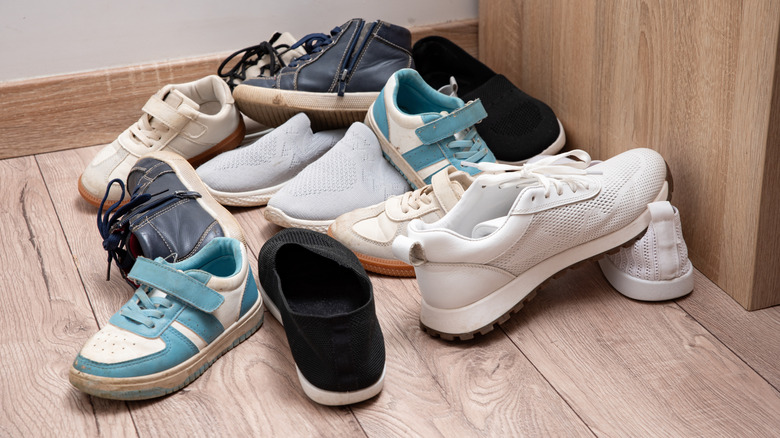 A jumbled pile of kids shoes on a wooden floor