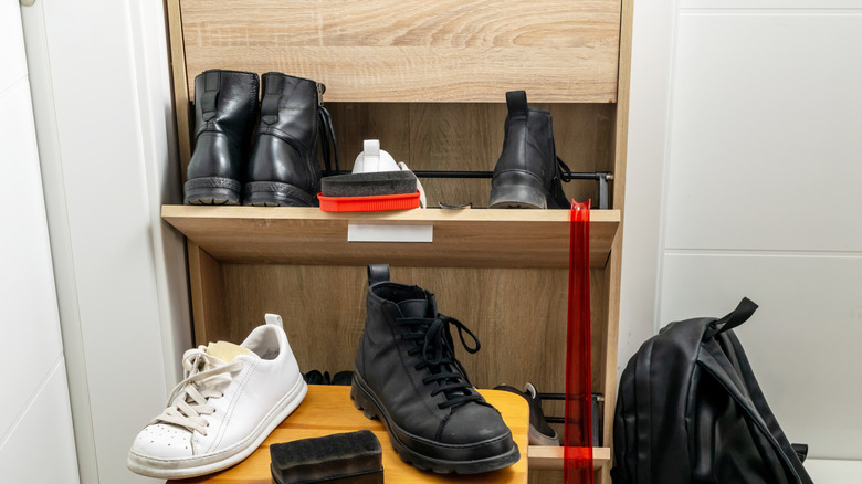 A flip-drawer shoe cabinet is open and full of shoes.