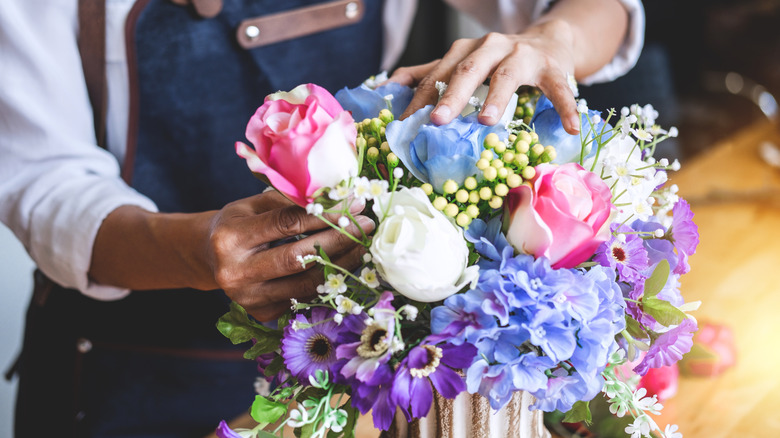 person adjusting bouquet of flowers in vase