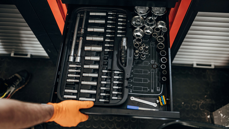Person opening drawer of drill bits and nuts in tool cabinet