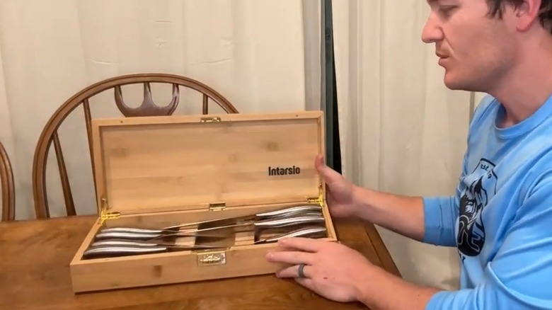 A person demonstrating a locking knife box on a wooden table