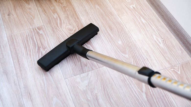 A close-up of a vacuum head cleaning a linoleum floor