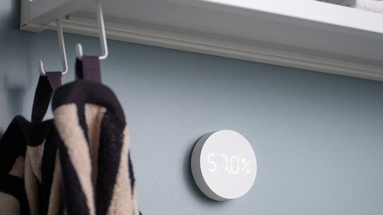 A small white humidity sensor mounted on a bathroom wall