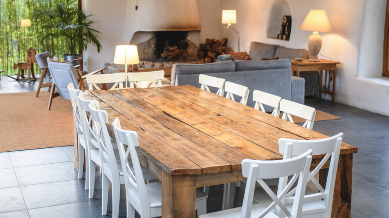 A handcrafted rustic table surrounded by white chairs in a stucco living room