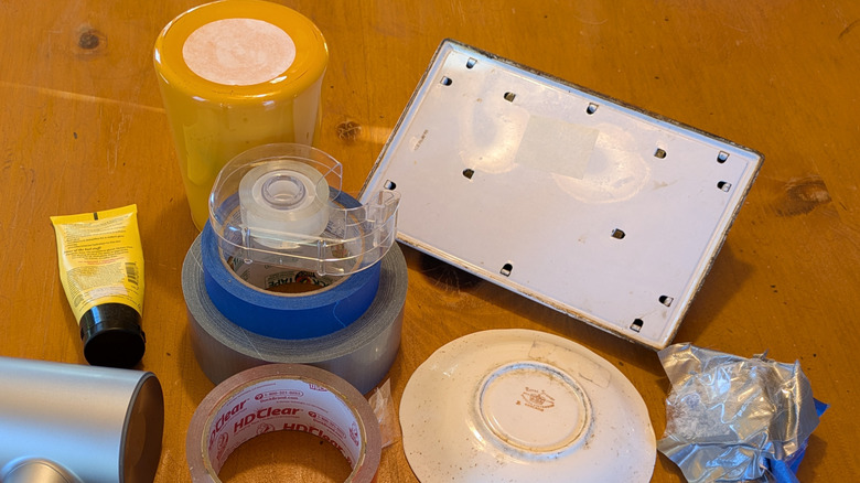 Items with price tags partially removed, tape, scissors, and a hairdryer on a wood table