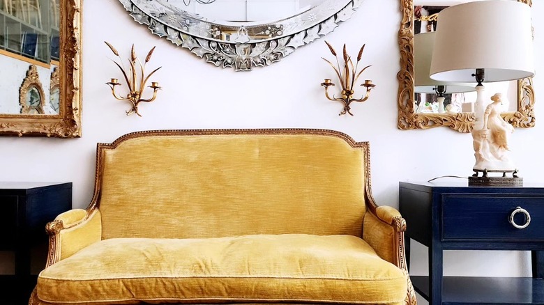 A small yellow sofa and pastel lamp on a blue table at a thrift store