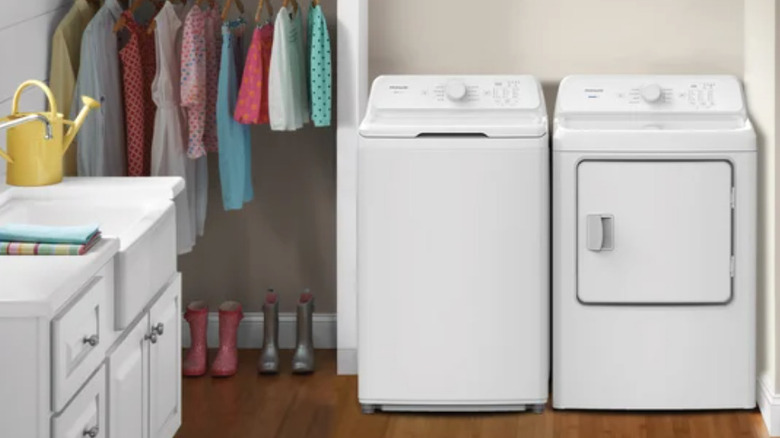Frigidaire 4.1 cu. ft. Top Load Washer with matching dryer in a laundry room with clothes hanging nearby