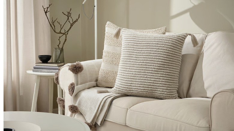 IKEA's KRYPLJUNG cushion cover on a beige couch next to another accent pillow in a very beige room