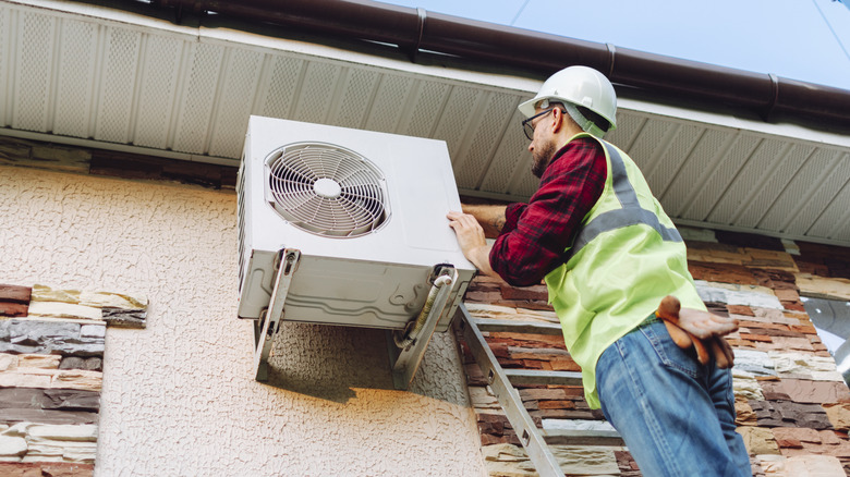 A technician servicing a wall-mounted heat pump