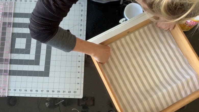 A DIYer places a fabric lining into a drawer and presses it so the adhesive will stick