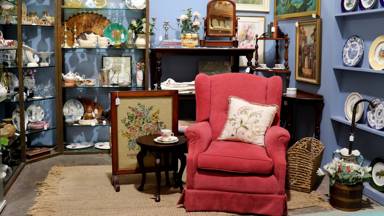 Red upholstered chair in a secondhand store sitting in front of shelves of collectibles