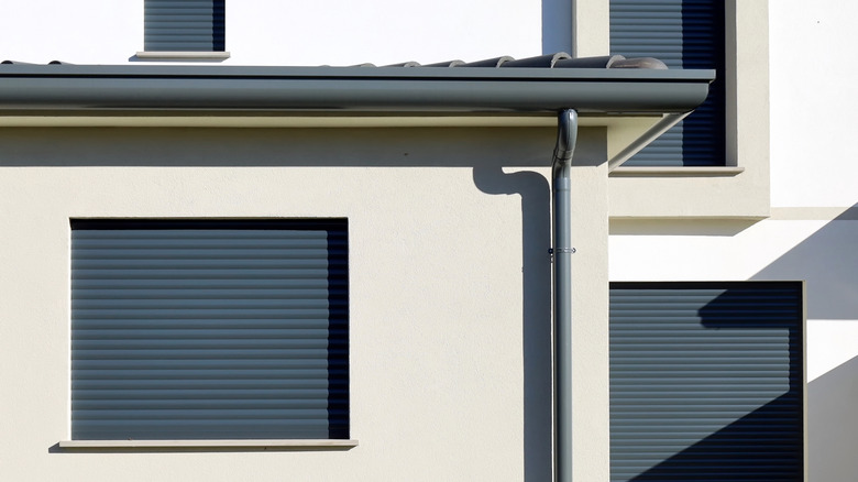 A modern residential building with dark gray rolling shutters