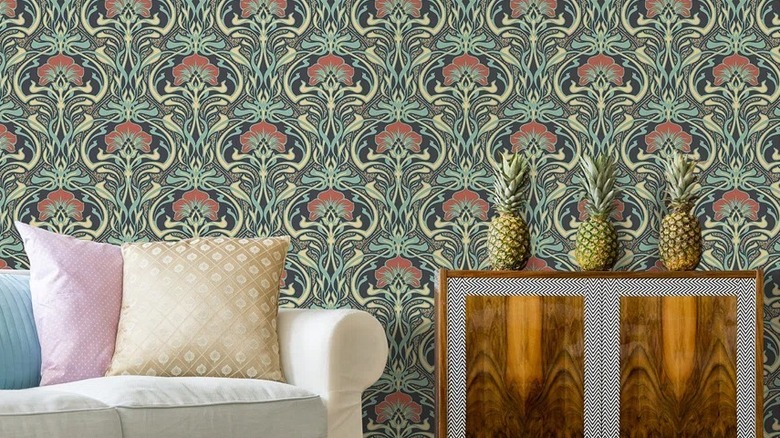 A floral green wallpaper design in a living room with a side table and pineapples