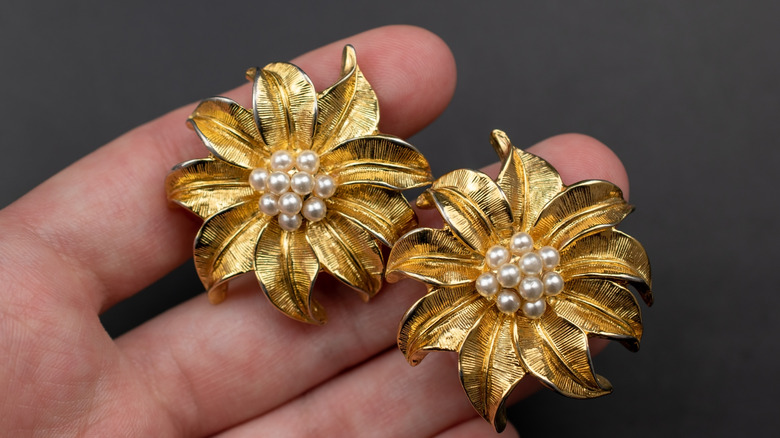 Close up of vintage gold floral-patterned earrings with pearl details.