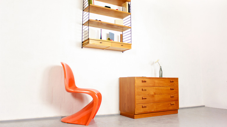 A mid-century room setting with an orange Panton chair