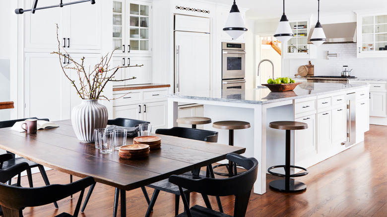 A bright modern kitchen with a wood table and wood floors.