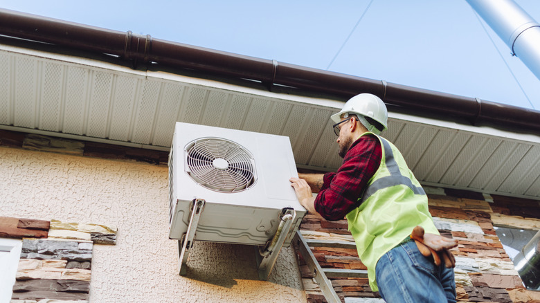 A technician working on a heat pump outside of a building