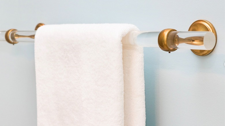 Lucite towel bar with brass brackets and white lush towel hanging.