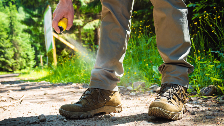 Man spraying boots with insect repellent