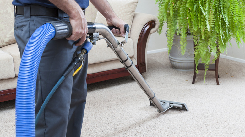 A man steam cleaning white carpet