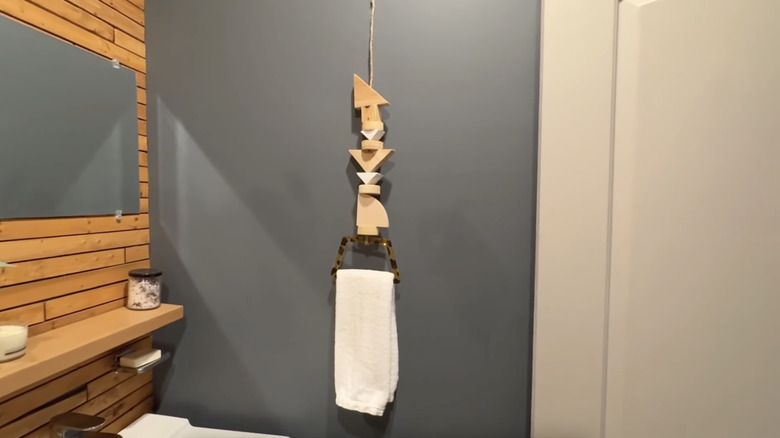 A DIY hand towel hanger made from geometric wood blocks and a handbag handle hangs in a bathroom.