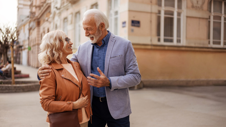 A senior couple smiling at each other in a beautiful European city