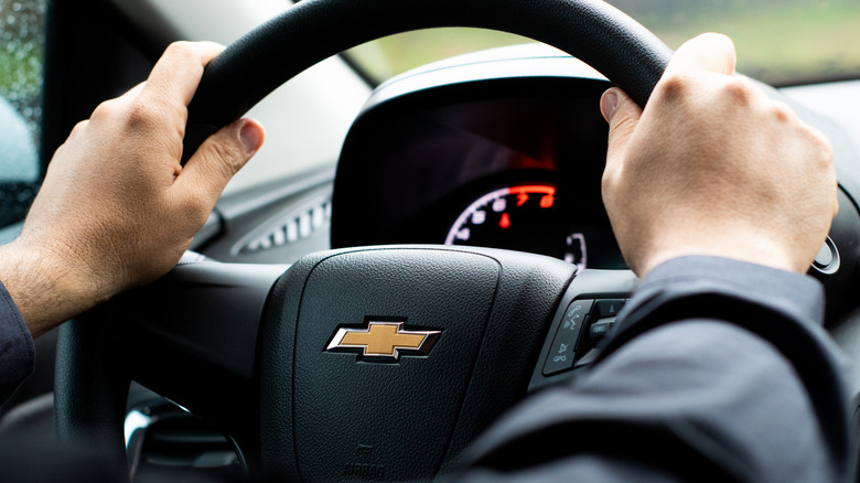 A man's hand on a Chevrolet steering wheel