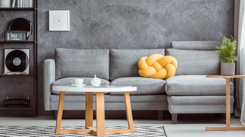 A gray-drenched living room with one bright yellow accent pillow