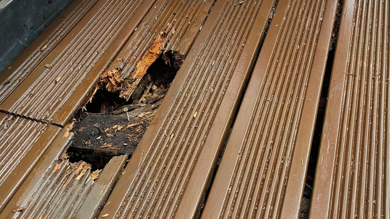 A hole in a wooden deck with a nail sticking out