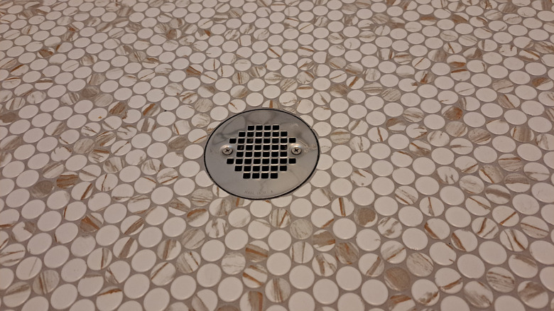 Penny tiles on a shower floor with a drain.