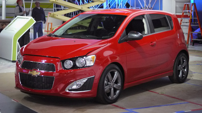 A red Chevrolet Sonic sits on the display floor as workers prepare for the Chicago Auto Show